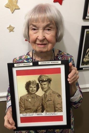 Mary, resident at Barkley Place, poses with a photo of her and her husband from their time in the military.