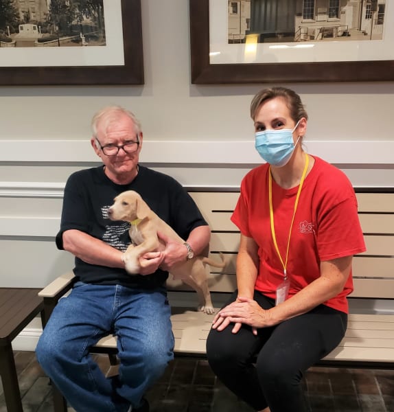 Man holds puppy in his arms sitting next to woman on a bench