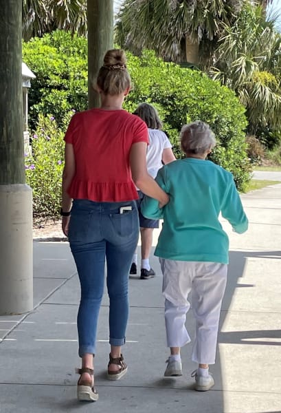 One Carolina Park (SC) team member helps one of the residents walk down the boardwalk,