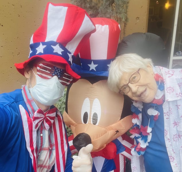 A First Hill (WA) team member and resident pose next to the Fourth of July Mickey Mouse.