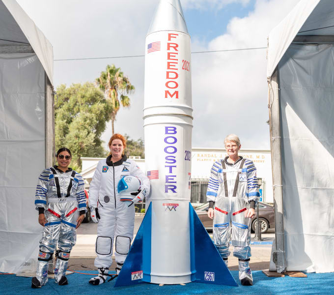 The Bankers Hill team poses in front of the custom rocket with their astronaut uniforms on.